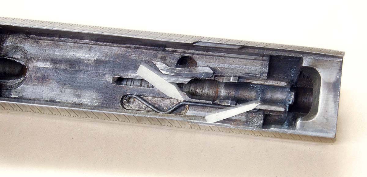 The first cartridge stop was a bent wire spring (thick arrow) with its tip protruding through the cartridge guide (thin arrow).